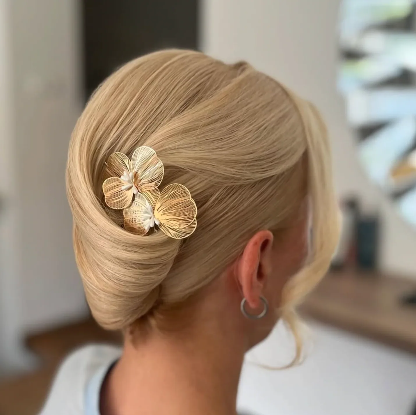 Elegancki kok francuski na blond włosach ze złotą ozdobą w kształcie storczyka